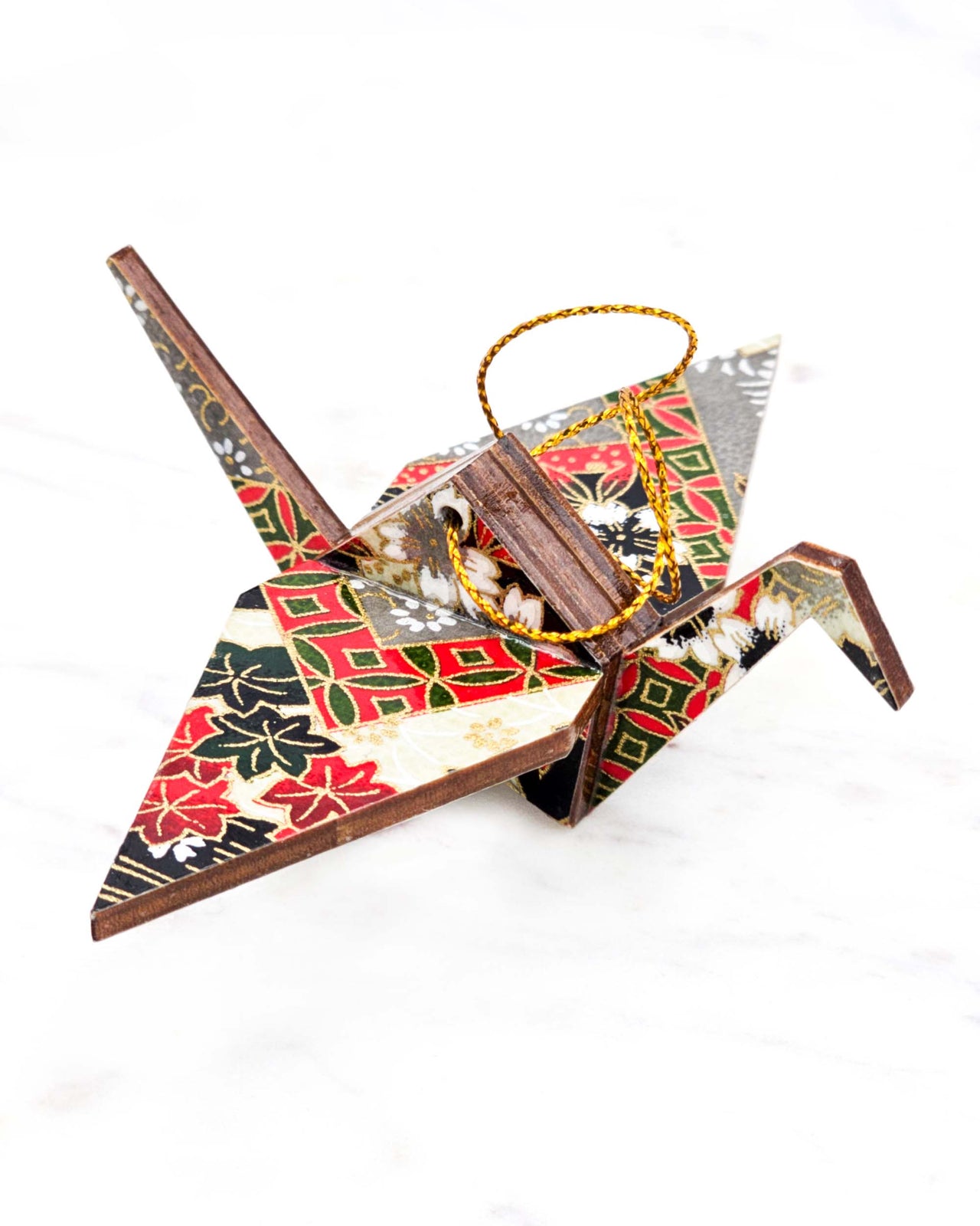 Small wooden origami crane ornament featuring white, black, and red maple leaves and cherry blossoms and red and green shippo patterns on a gray and cream background with metallic gold accents.