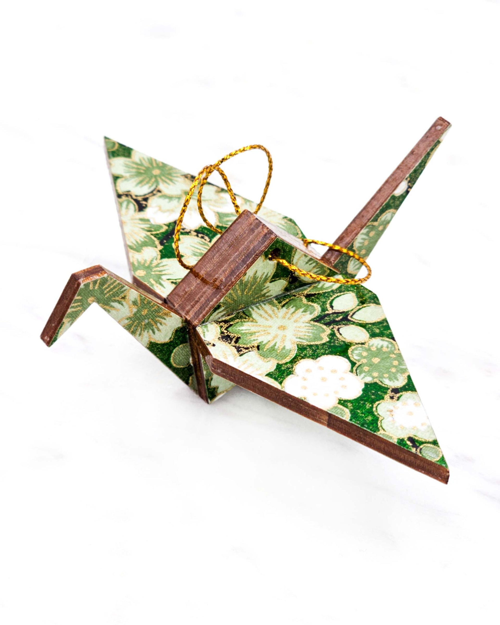Small wooden origami crane ornament featuring green and white cherry and plum blossoms on a green background with metallic gold accents.