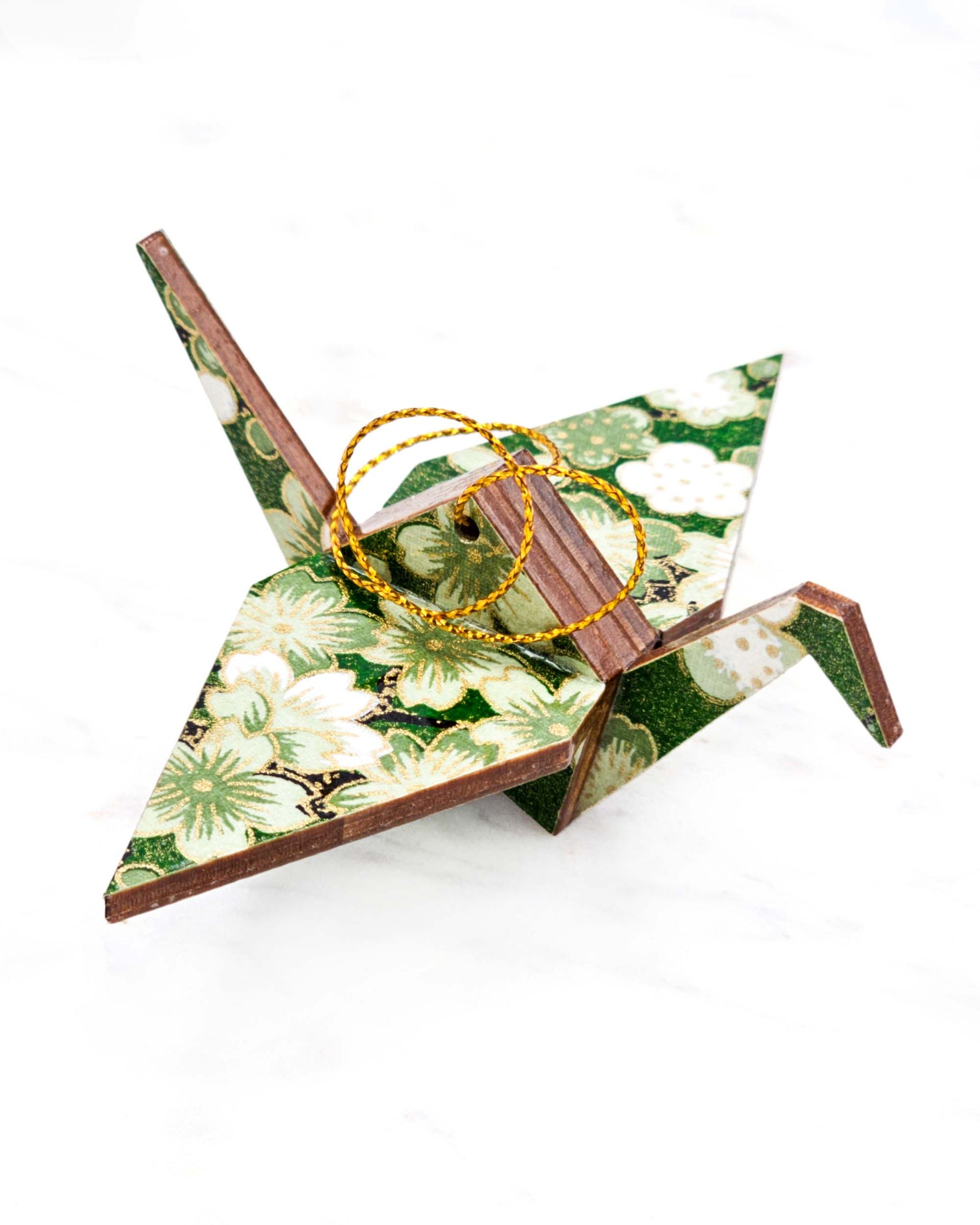 Small wooden origami crane ornament featuring green and white cherry and plum blossoms on a green background with metallic gold accents.
