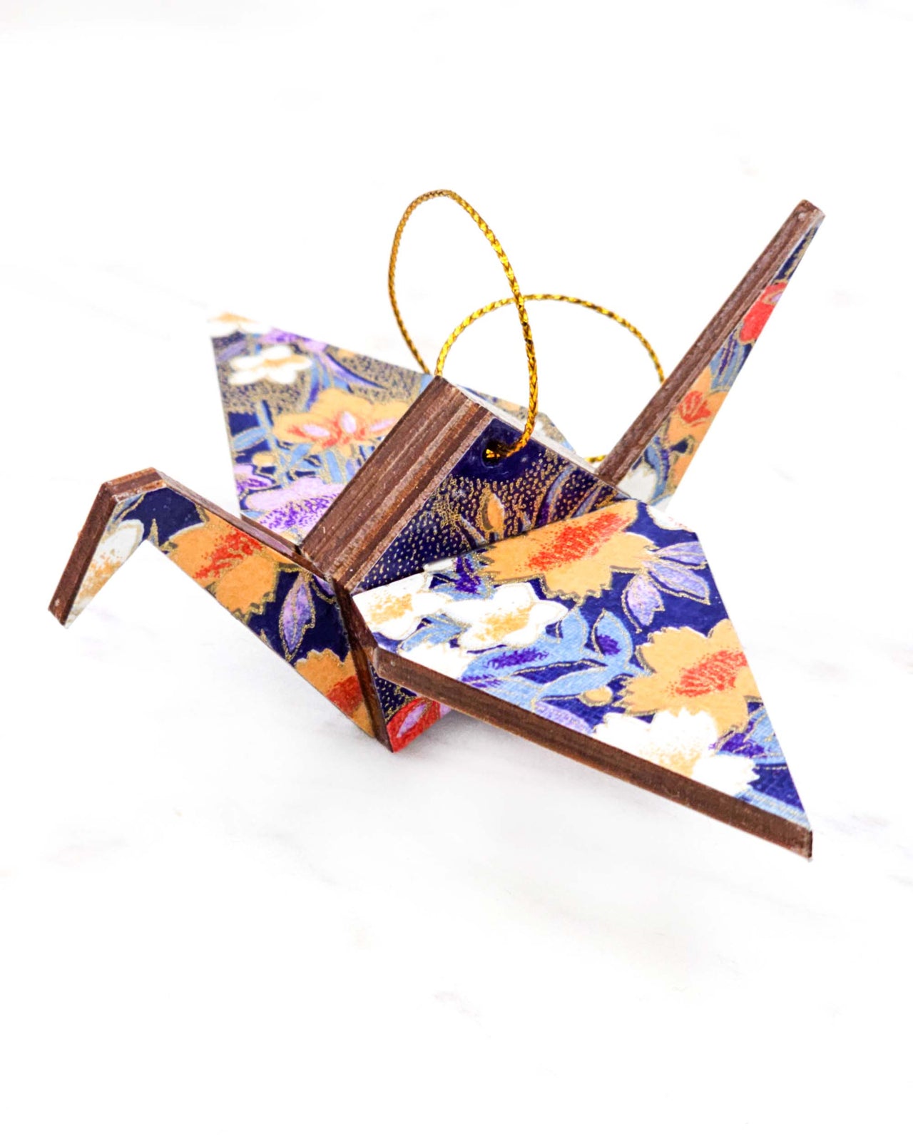 Small wooden origami crane ornament featuring orange, purple, and white irises on a dark blue background with metallic gold accents.