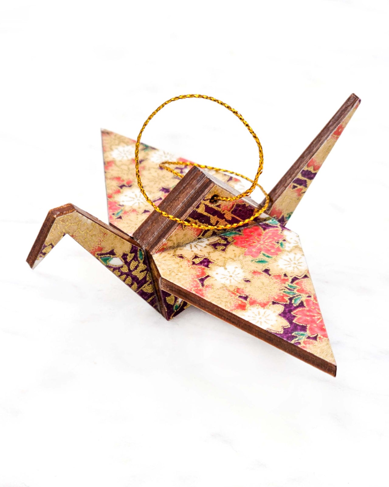 Small wooden origami crane ornament featuring purple and pink and cream cherry blossoms on a dark purple background with metallic gold accents.