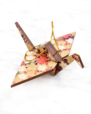 Small wooden origami crane ornament featuring purple and pink and cream cherry blossoms on a dark purple background with metallic gold accents.