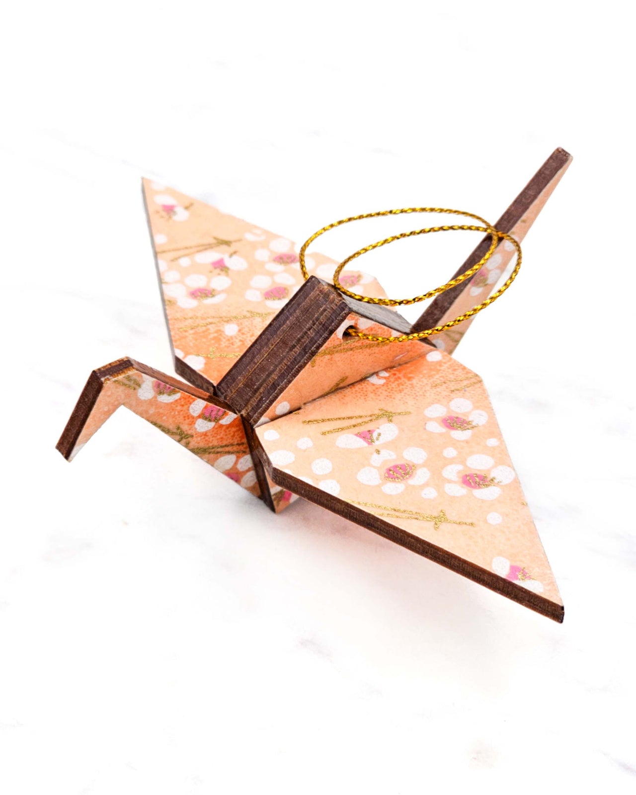 Small wooden origami crane ornament featuring white plum blossoms and gold matsubas on an orange gradient background with metallic gold accents.