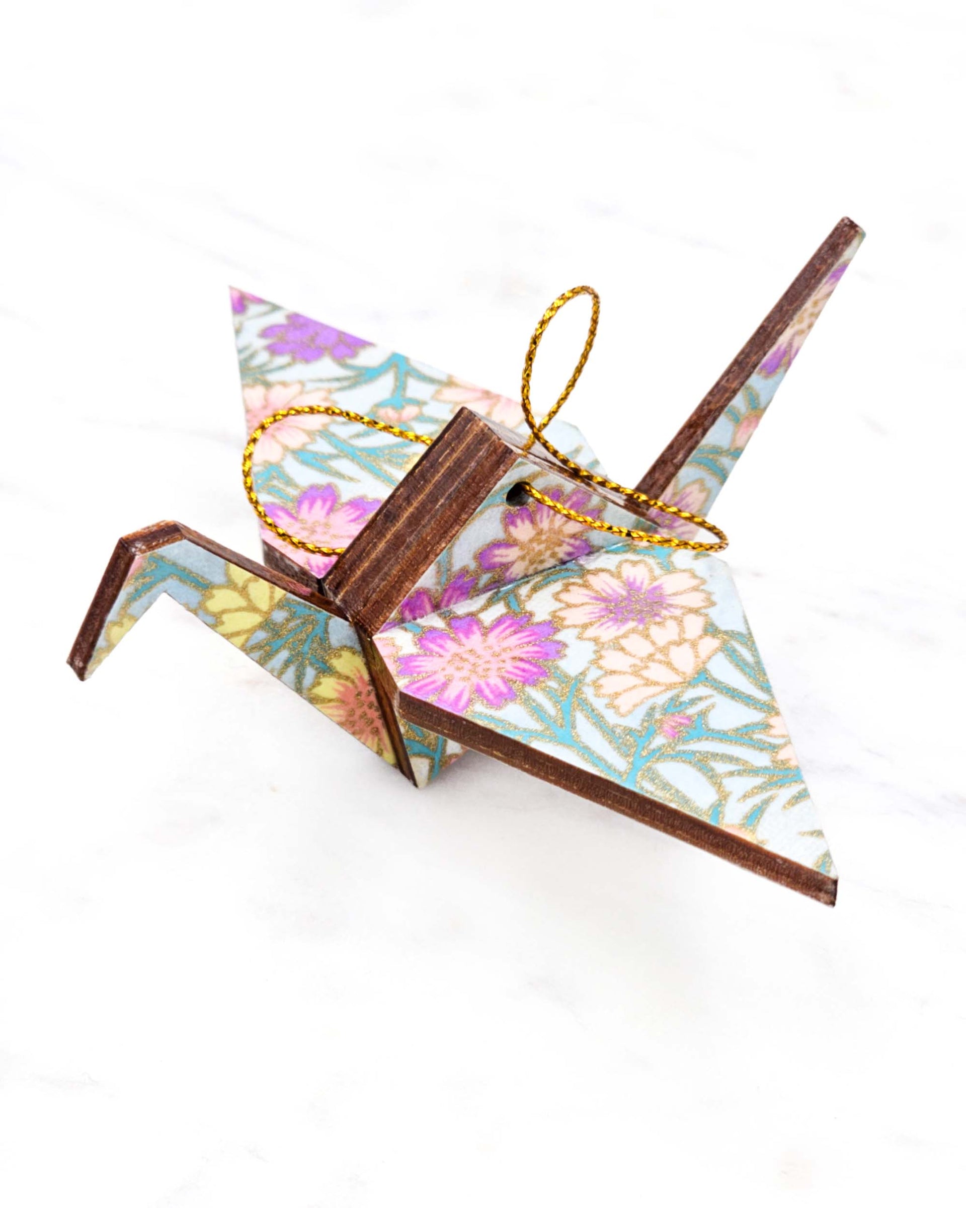 Small wooden origami crane ornament featuring white and pink cherry blossoms on a dark blue background with metallic gold accents.