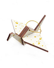 Small wooden origami crane ornament featuring a white traditional Japanese sayagata design on a white background with metallic gold details.
