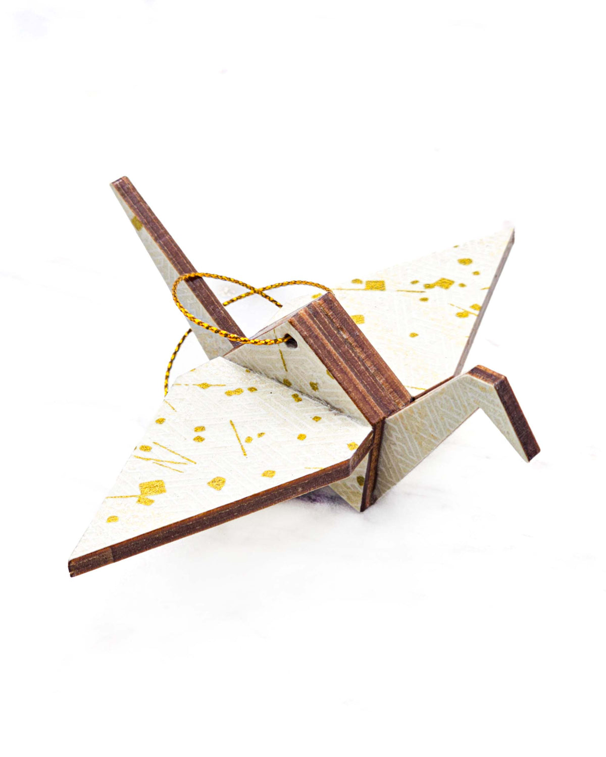 Small wooden origami crane ornament featuring a white traditional Japanese sayagata design on a white background with metallic gold details.
