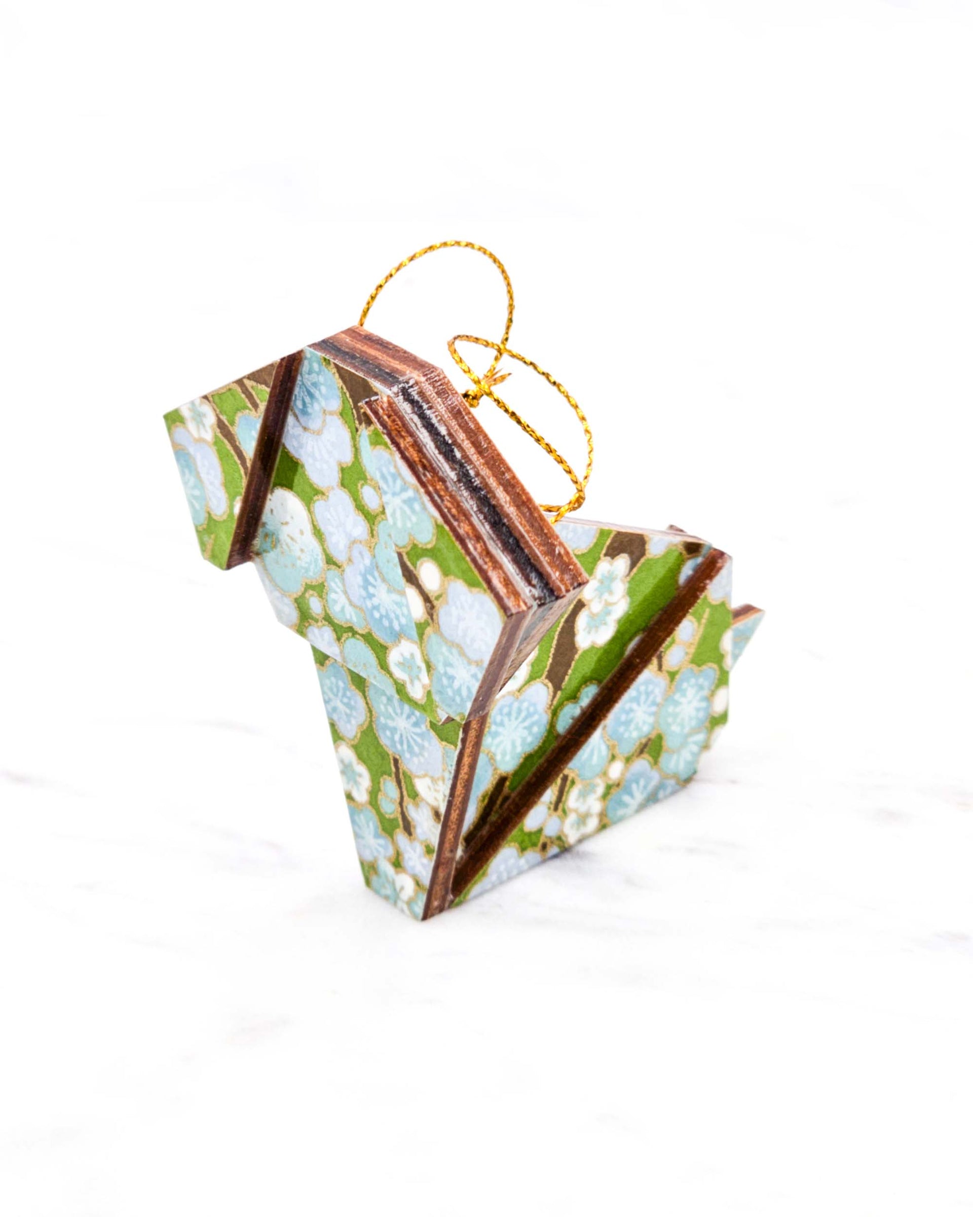 Small wooden origami dog ornament featuring light blue and white plum blossoms with brown branches on a green background with metallic gold details.