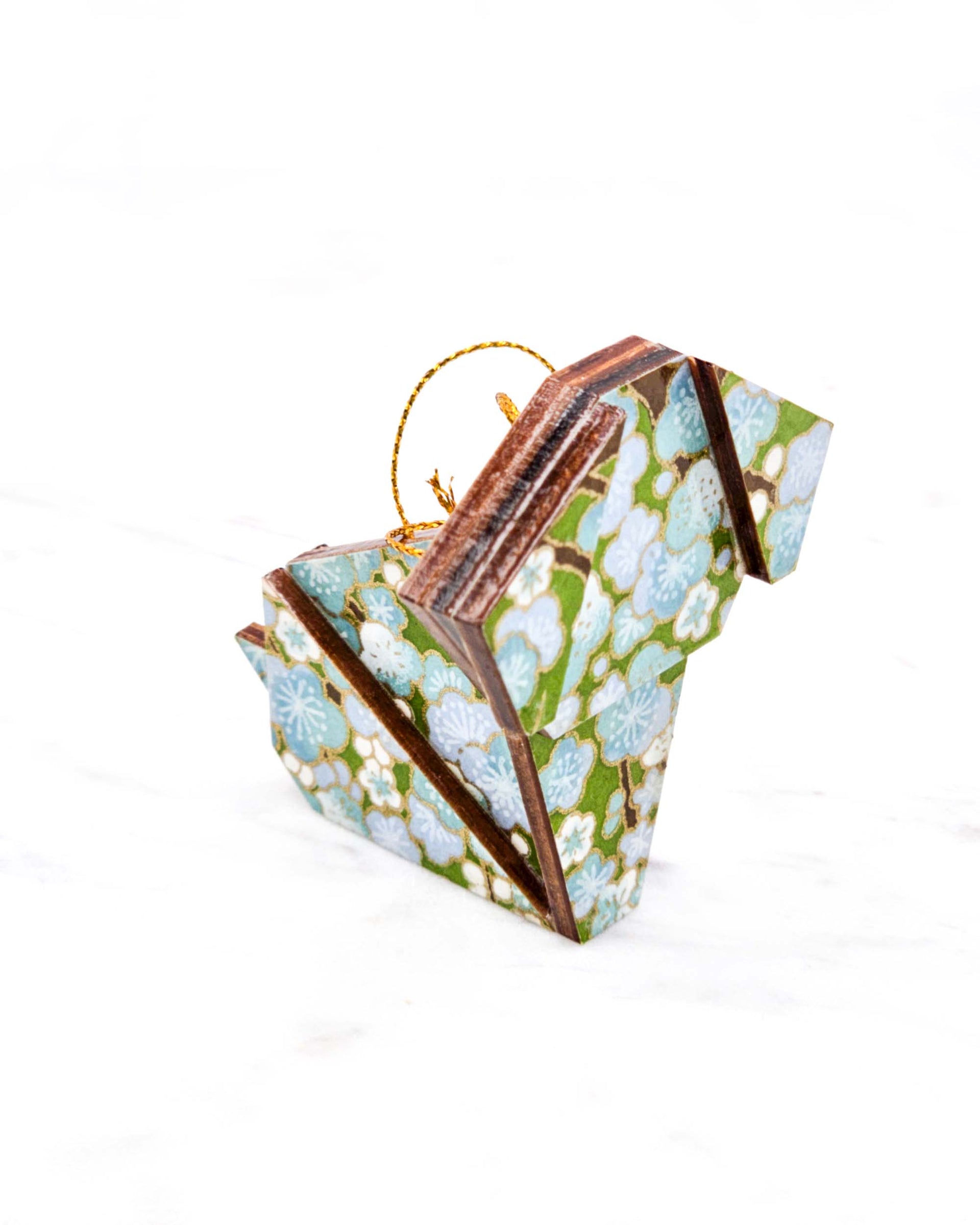 Small wooden origami dog ornament featuring light blue and white plum blossoms with brown branches on a green background with metallic gold details.
