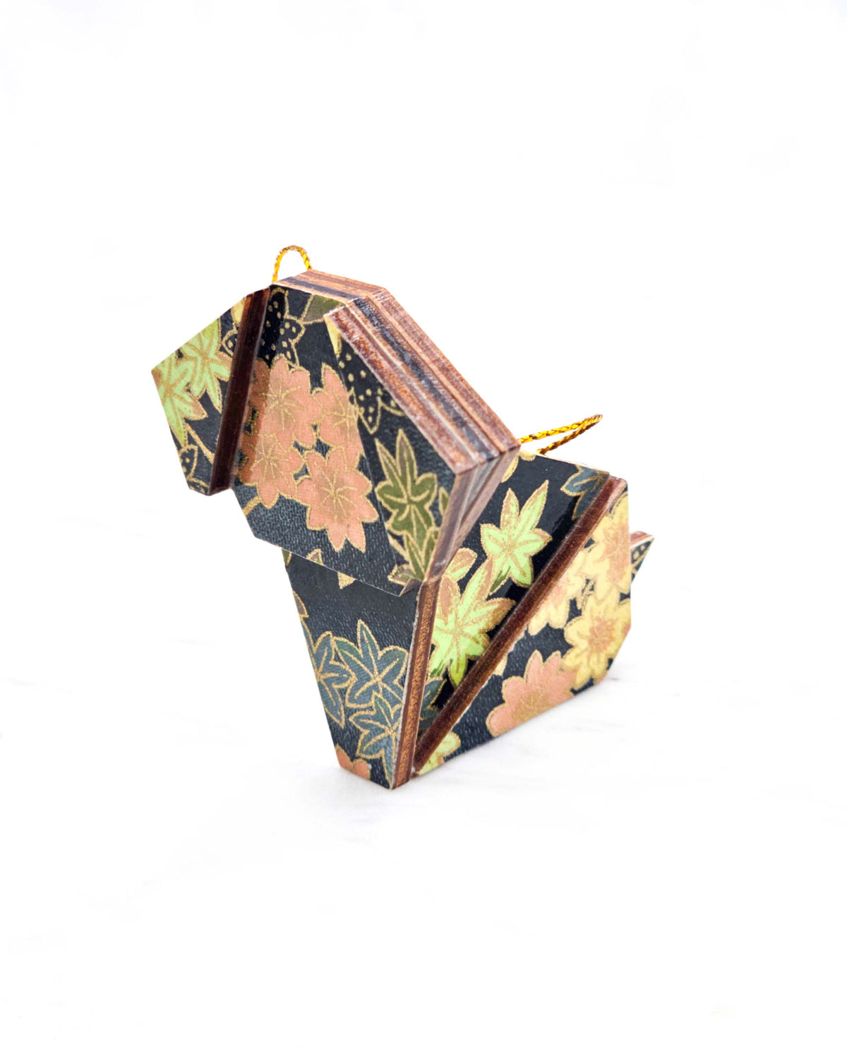 Small wooden origami dog ornament featuring assorted green, pink, beige, and gray maple leaves with dark gray and metallic gold dotted maple leaves on a dark gray background.