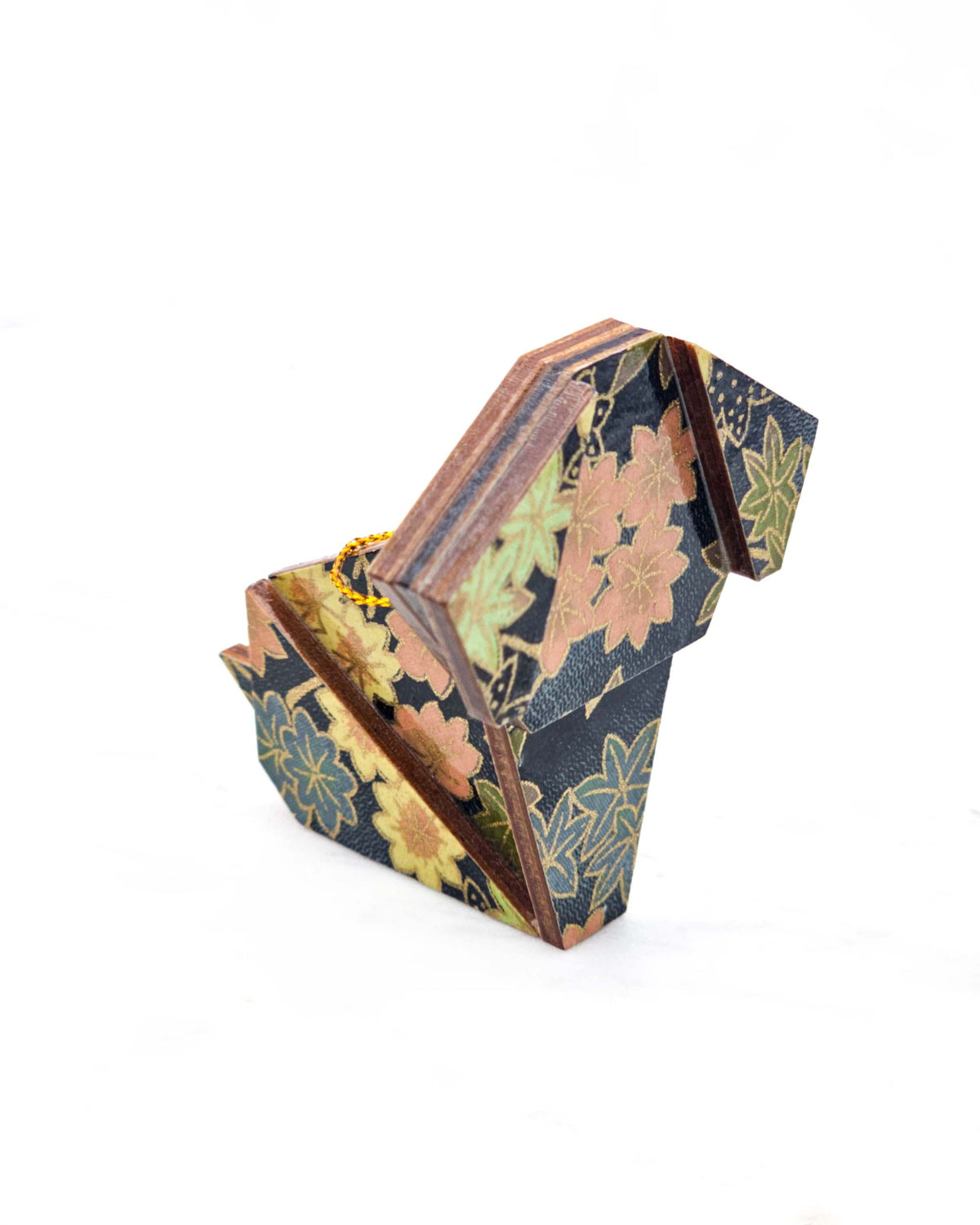 Small wooden origami dog ornament featuring assorted green, pink, beige, and gray maple leaves with dark gray and metallic gold dotted maple leaves on a dark gray background.