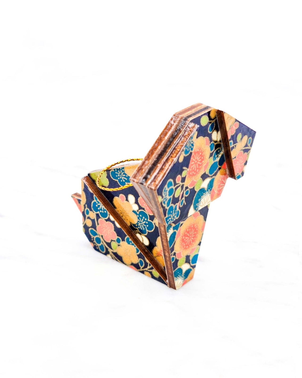 Small wooden origami dog ornament featuring orange, blue, green, and cream plum blossoms on a dark blue background with metallic gold details.