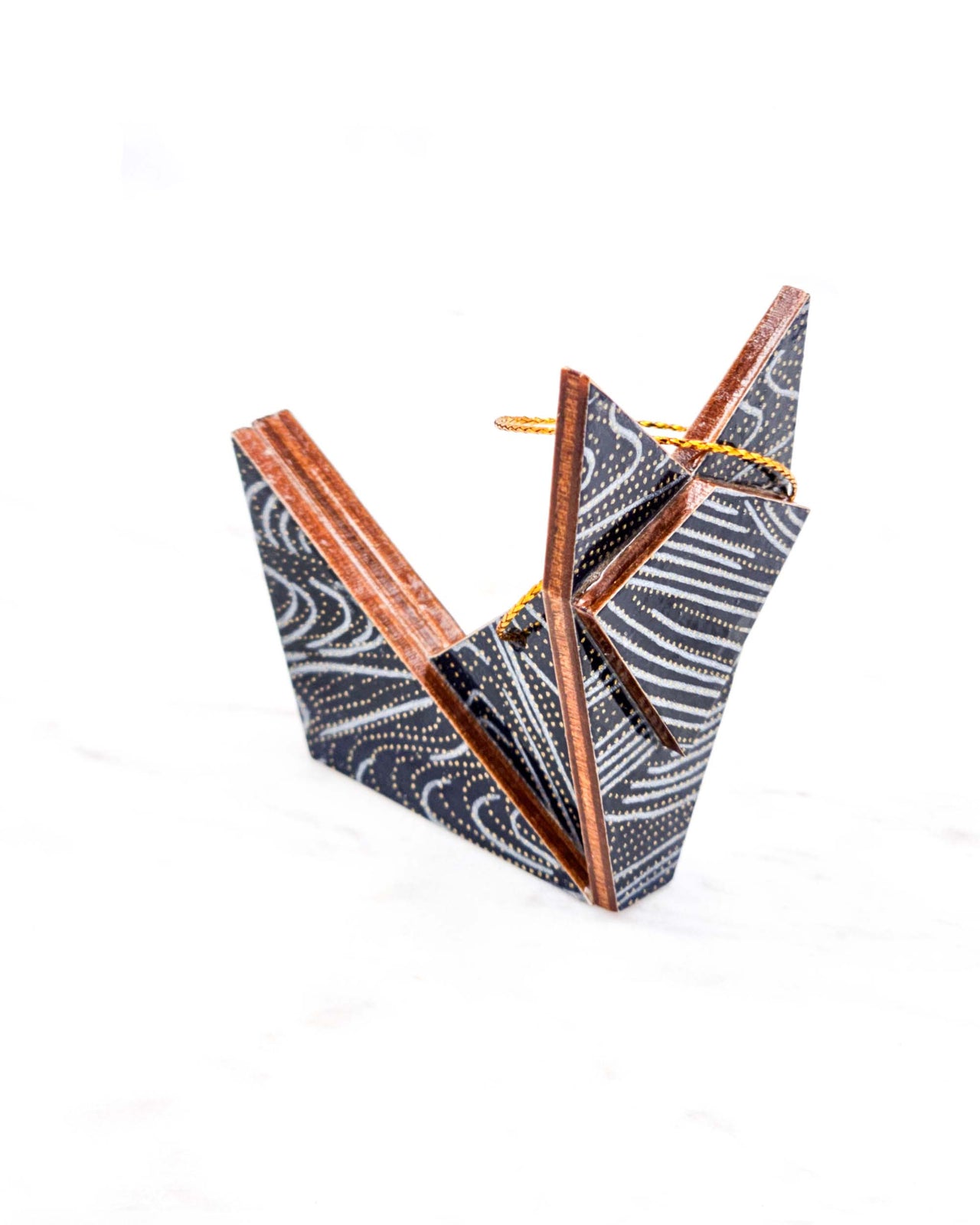 Small wooden origami fox ornament featuring metallic silver and gold ripples on a black background.