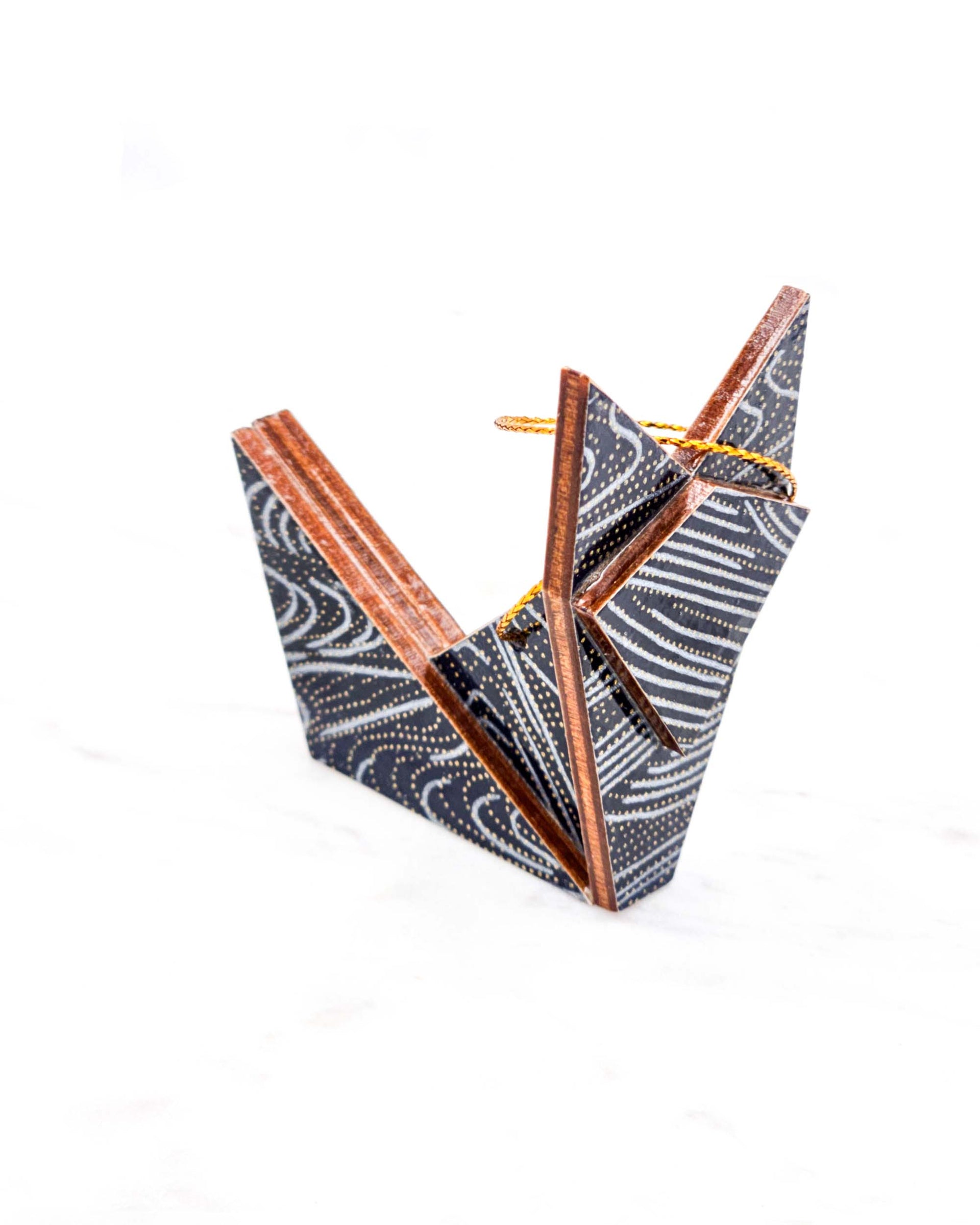 Small wooden origami fox ornament featuring metallic silver and gold ripples on a black background.