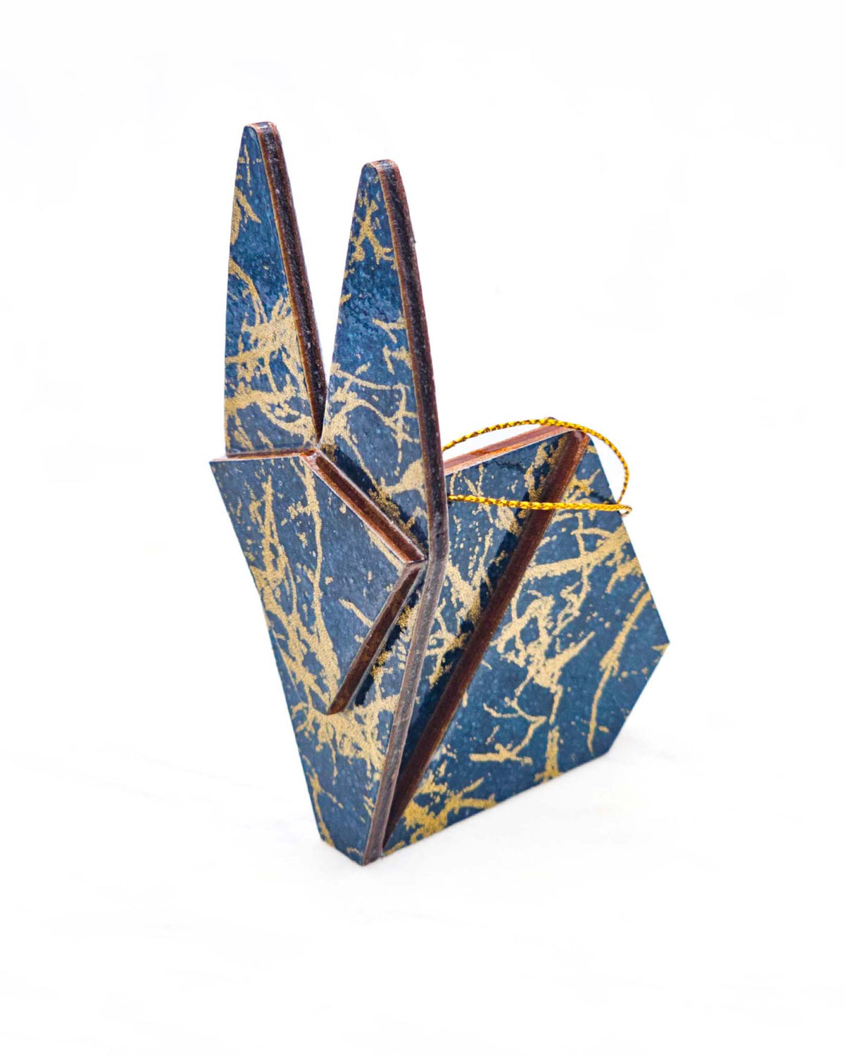 Small wooden origami rabbit ornament featuring metallic gold fibers in the style of traditional unryu paper on a dark blue background.