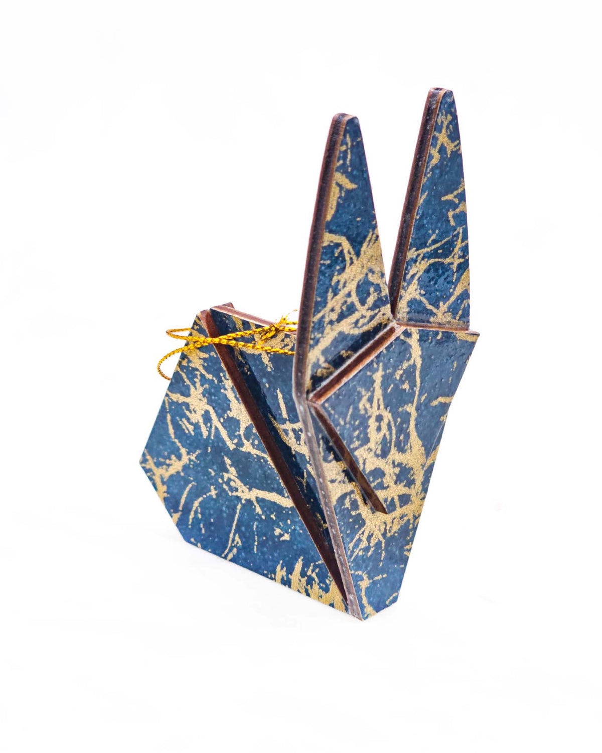 Small wooden origami rabbit ornament featuring metallic gold fibers in the style of traditional unryu paper on a dark blue background.