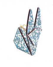 Large wooden origami rabbit ornament featuring small white flower bushes over a blue background with metallic gold details.
