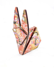Large wooden origami rabbit ornament featuring red and purple floral hand fans and gold floral ribbons on an orange gradient background covered in small white plum blossoms with metallic gold details.