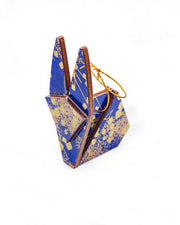 Small wooden origami rabbit ornament featuring scattered metallic gold geometric shapes and fine gold lines on a blue background.
