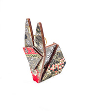 Small wooden origami rabbit ornament featuring red, gray, black, and off white patches with an assortment of various floral patterns and metallic gold details.