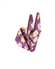 Small wooden origami rabbit ornament featuring pink and white cherry blossoms on a purple background with light asanoha (hemp leaf) and seigaiha (wave crest) silhouettes and metallic gold details.
