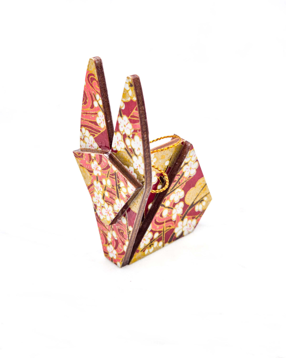 Small wooden origami rabbit ornament featuring white plum blossoms with dark brown branches on a maroon red and gold background.
