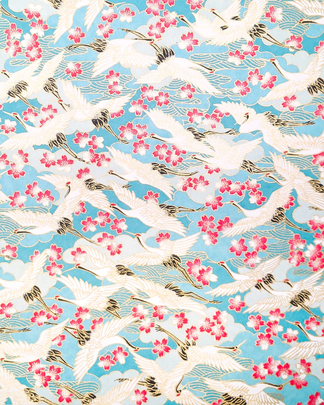Japanese chiyogami paper featuring flying white cranes and pink cherry blossoms a light blue background with metallic gold accents.