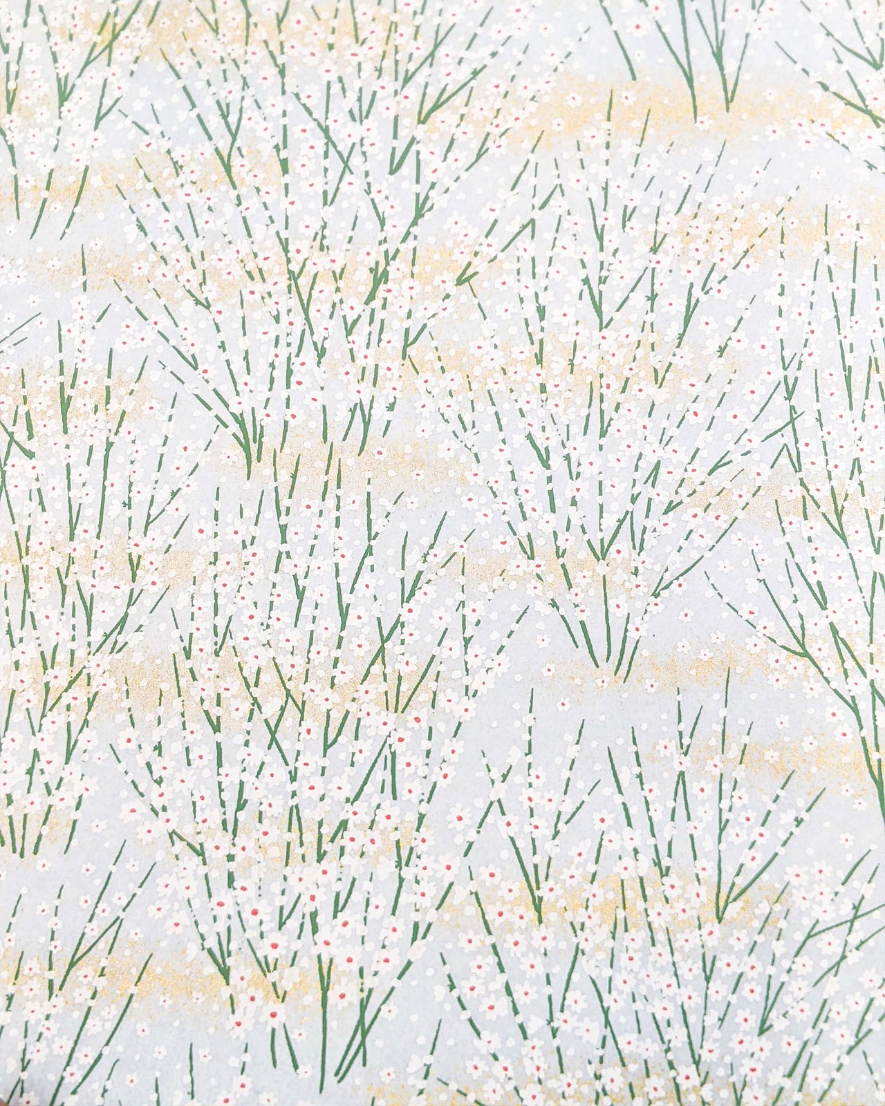 Japanese chiyogami paper featuring small white flower bushes over a light blue background with metallic gold accents.