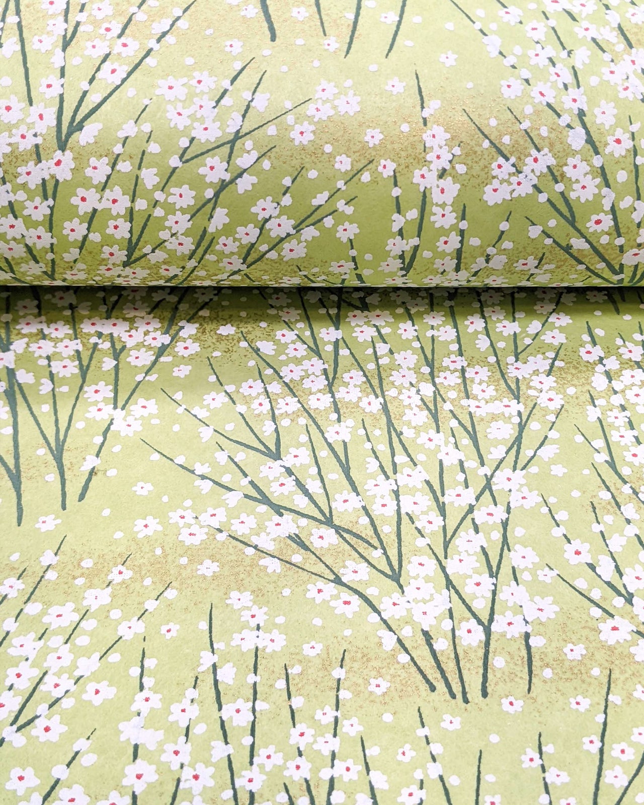 Japanese chiyogami paper featuring small white flower bushes over a yellow green background with metallic gold accents.
