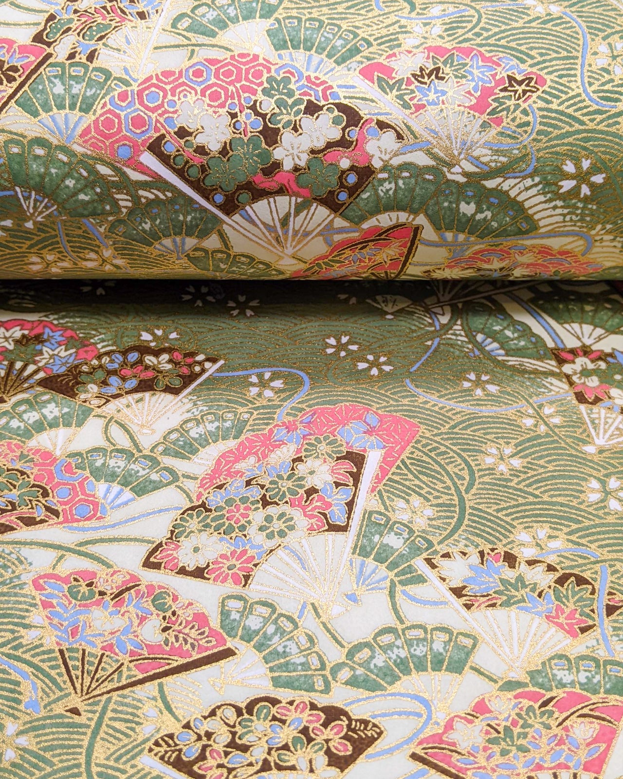 Japanese chiyogami featuring floral hand fans on a green wave crest background with metallic gold accents.