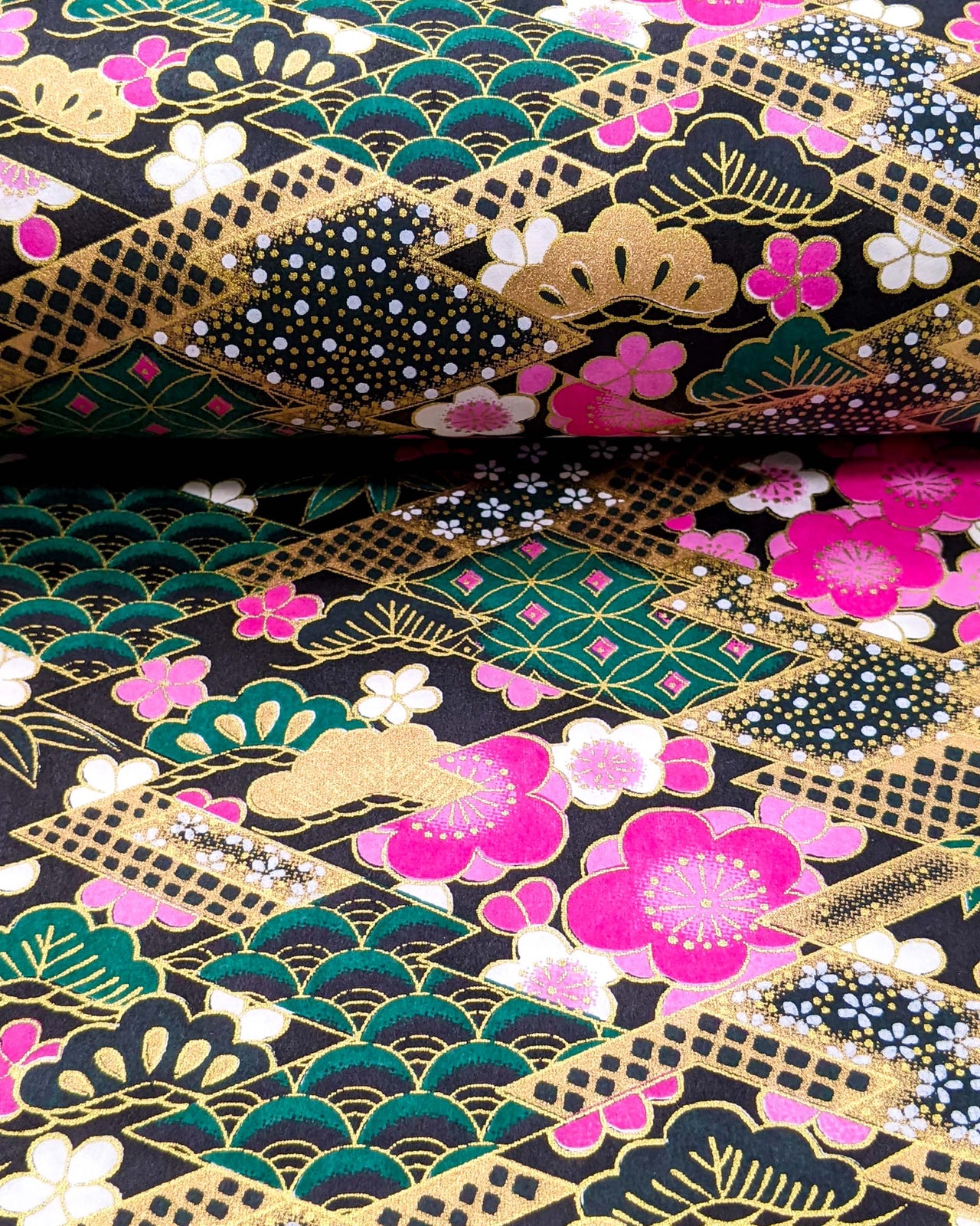 Japanese chiyogami paper featuring pink & white plum blossoms on a black & green background with metallic gold accents.