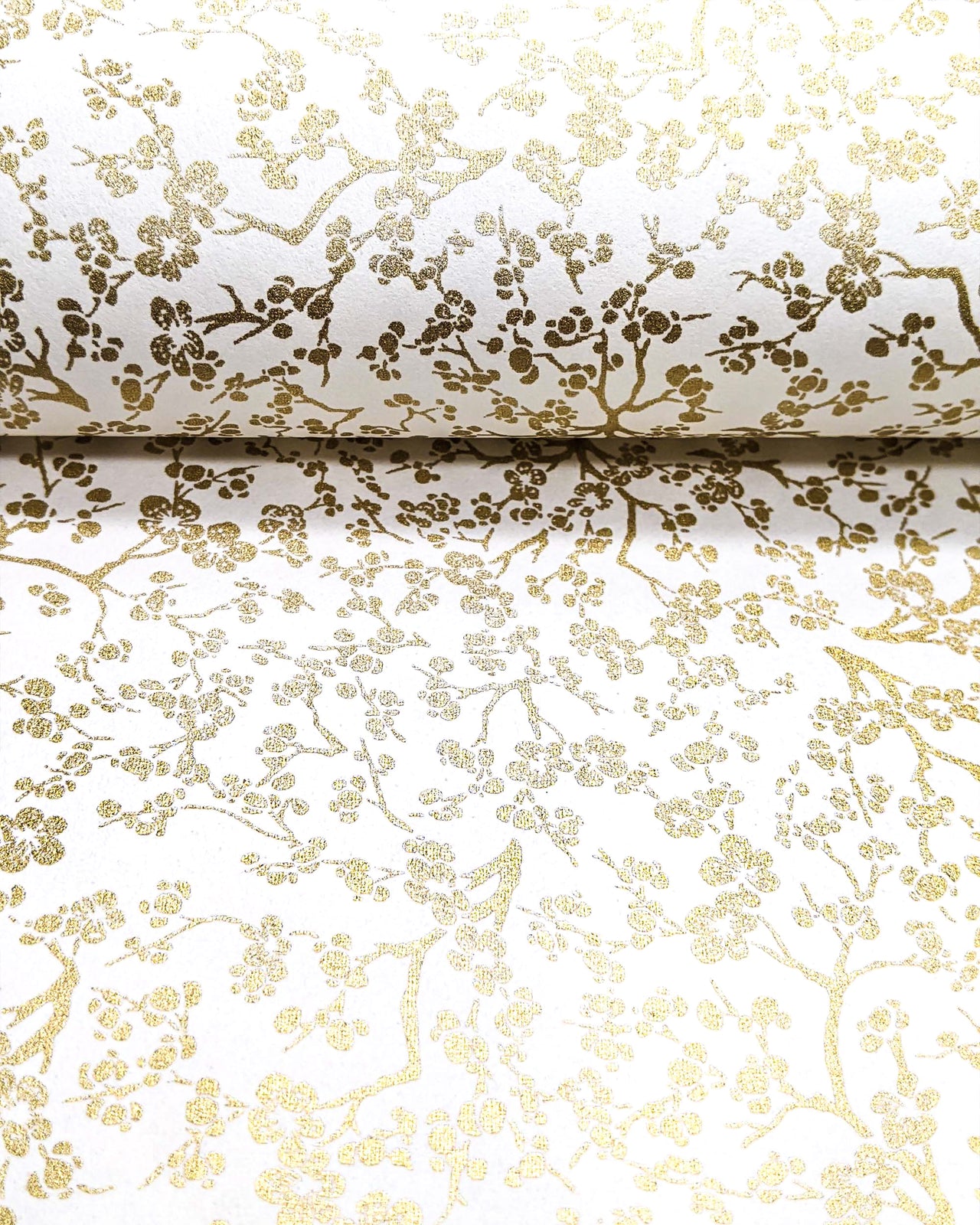 Japanese chiyogami paper featuring small metallic gold plum blossom branches on a white background.