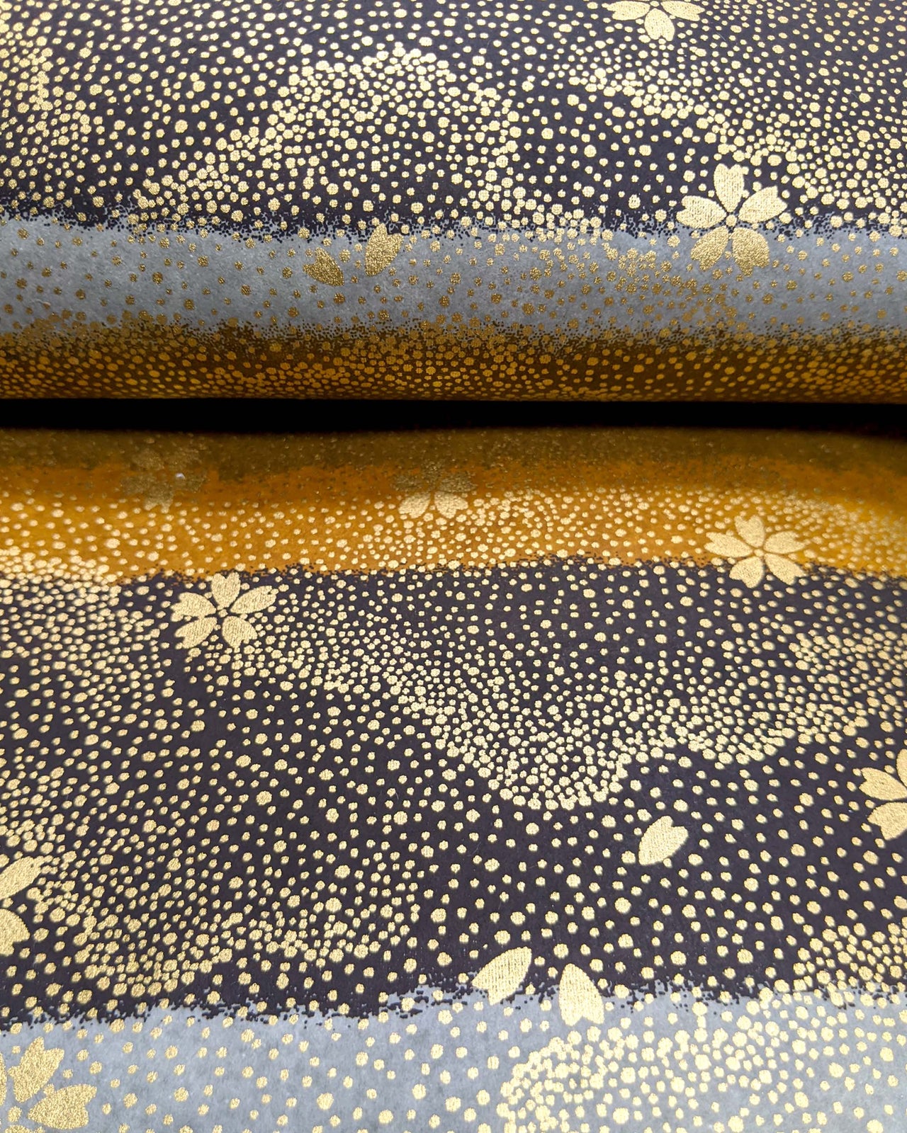 Japanese chiyogami paper featuring gold cherry blossoms on a black, gray, and brown striped background with metallic gold details.