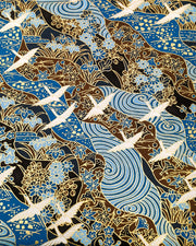 Japanese chiyogami paper featuring flying white cranes on a floral blue and brown background with metallic gold details