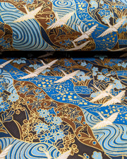 Japanese chiyogami paper featuring flying white cranes on a floral blue and brown background with metallic gold details