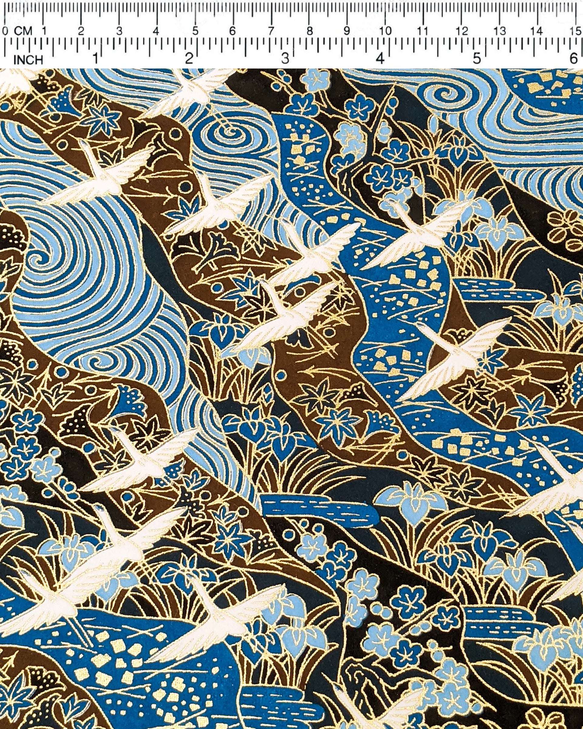 Japanese chiyogami paper featuring flying white cranes on a floral blue and brown background with metallic gold details