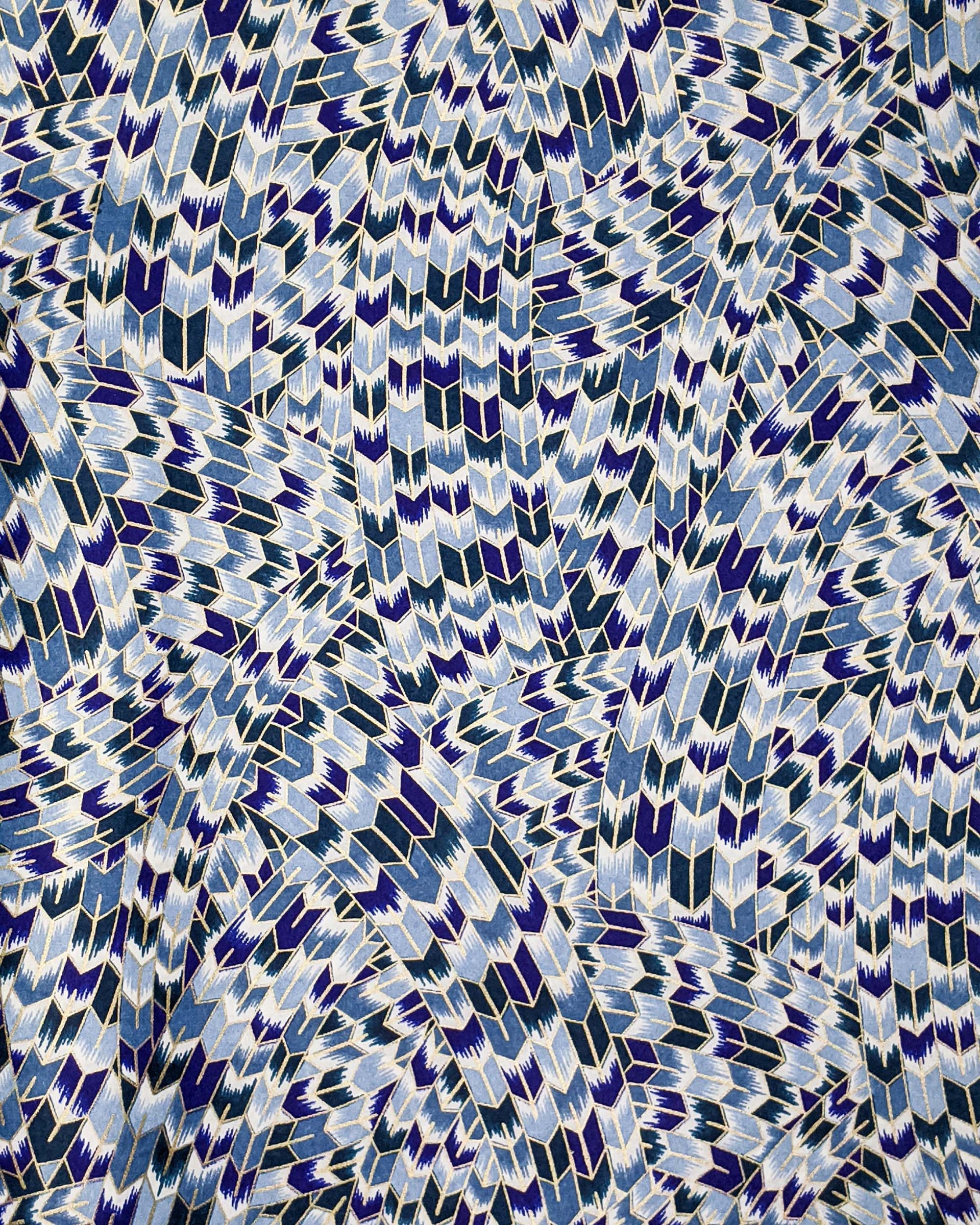 Japanese chiyogami paper featuring blue and white interlocking yagasuri (arrow) swirls with metallic gold details.