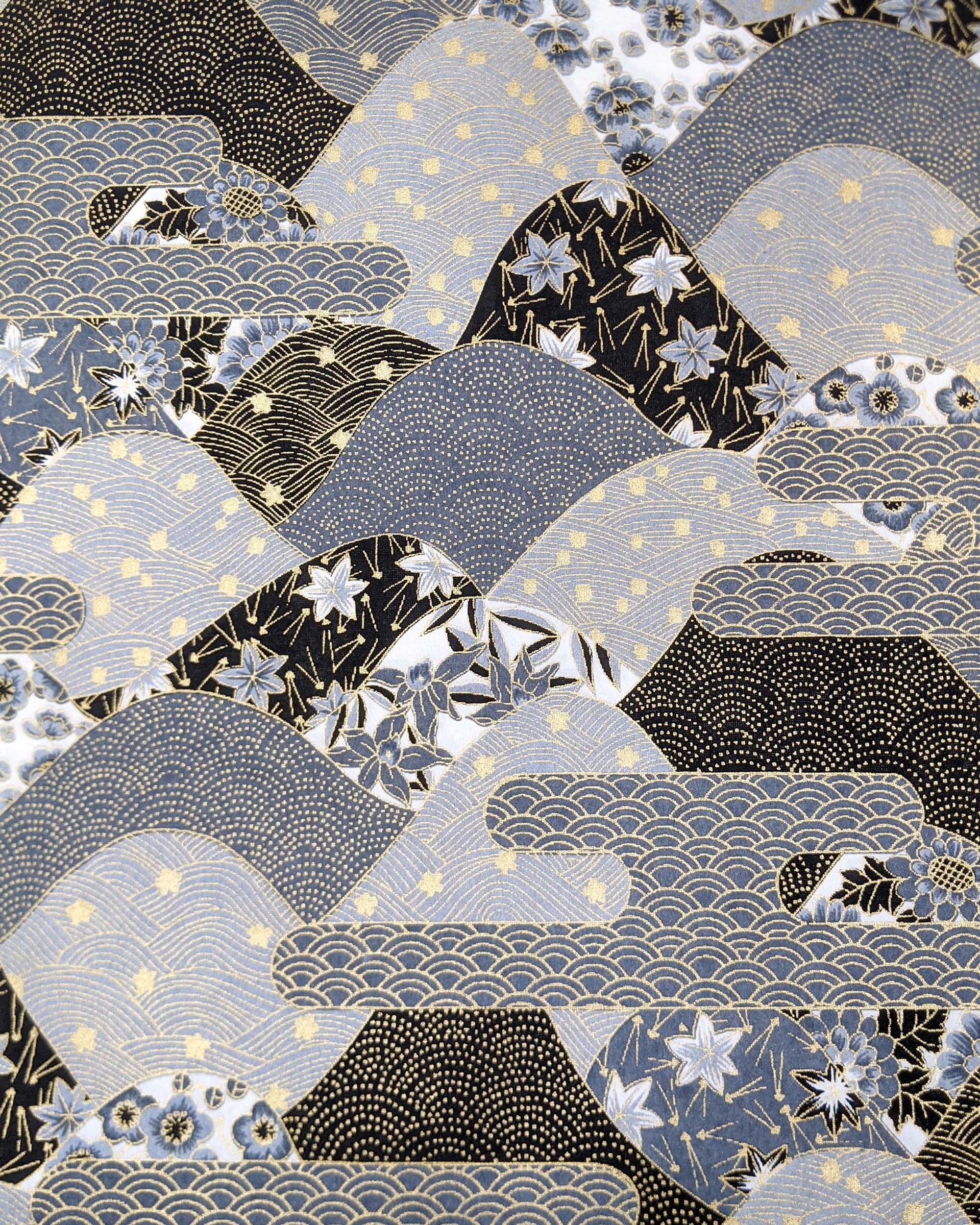 Japanese chiyogami paper featuring a black and gray hill design decorated with various Japanese flowers, maple leaves, and traditional geometric designs with metallic gold accents.