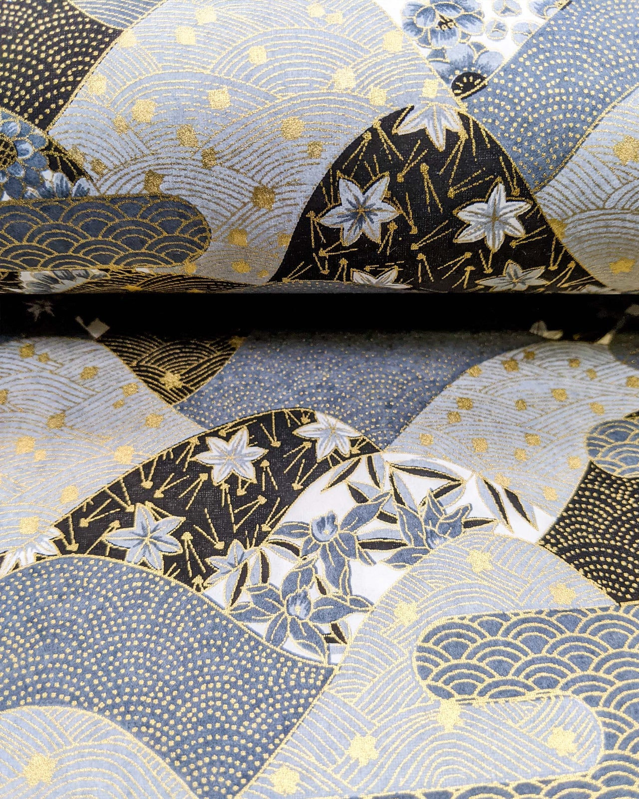 Japanese chiyogami paper featuring a black and gray hill design decorated with various Japanese flowers, maple leaves, and traditional geometric designs with metallic gold accents.