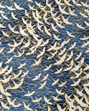 Japanese chiyogami paper featuring white flying cranes in a zigzag formation on a navy blue background with metallic gold details.