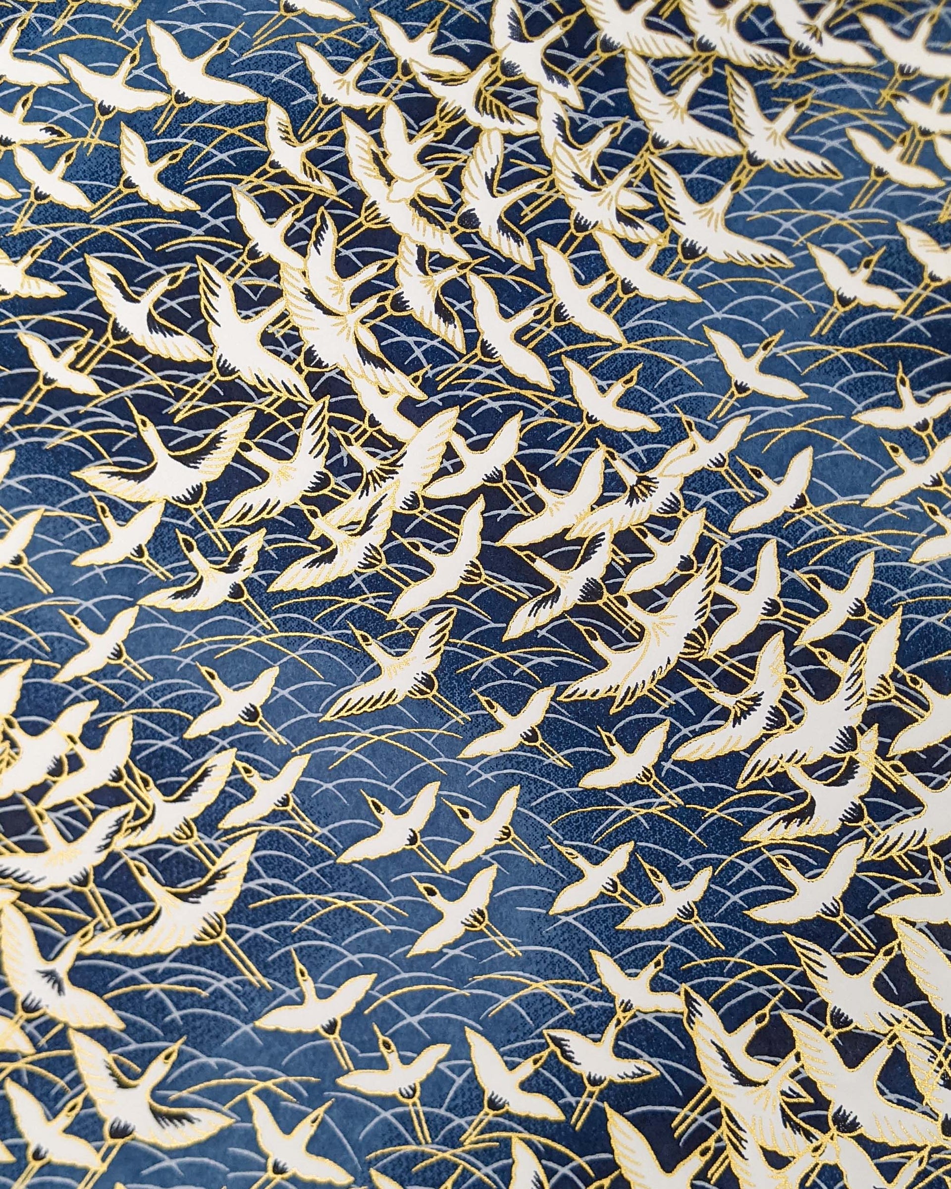 Japanese chiyogami paper featuring white flying cranes in a zigzag formation on a navy blue background with metallic gold details.