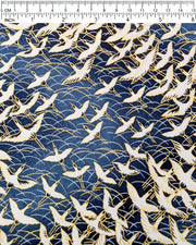 Japanese chiyogami paper featuring white flying cranes in a zigzag formation on a navy blue background with metallic gold details, shown next to a ruler for size reference.