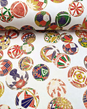 Japanese chiyogami paper featuring an assortment of colorful Japanese temari balls on a white background with metallic gold details.