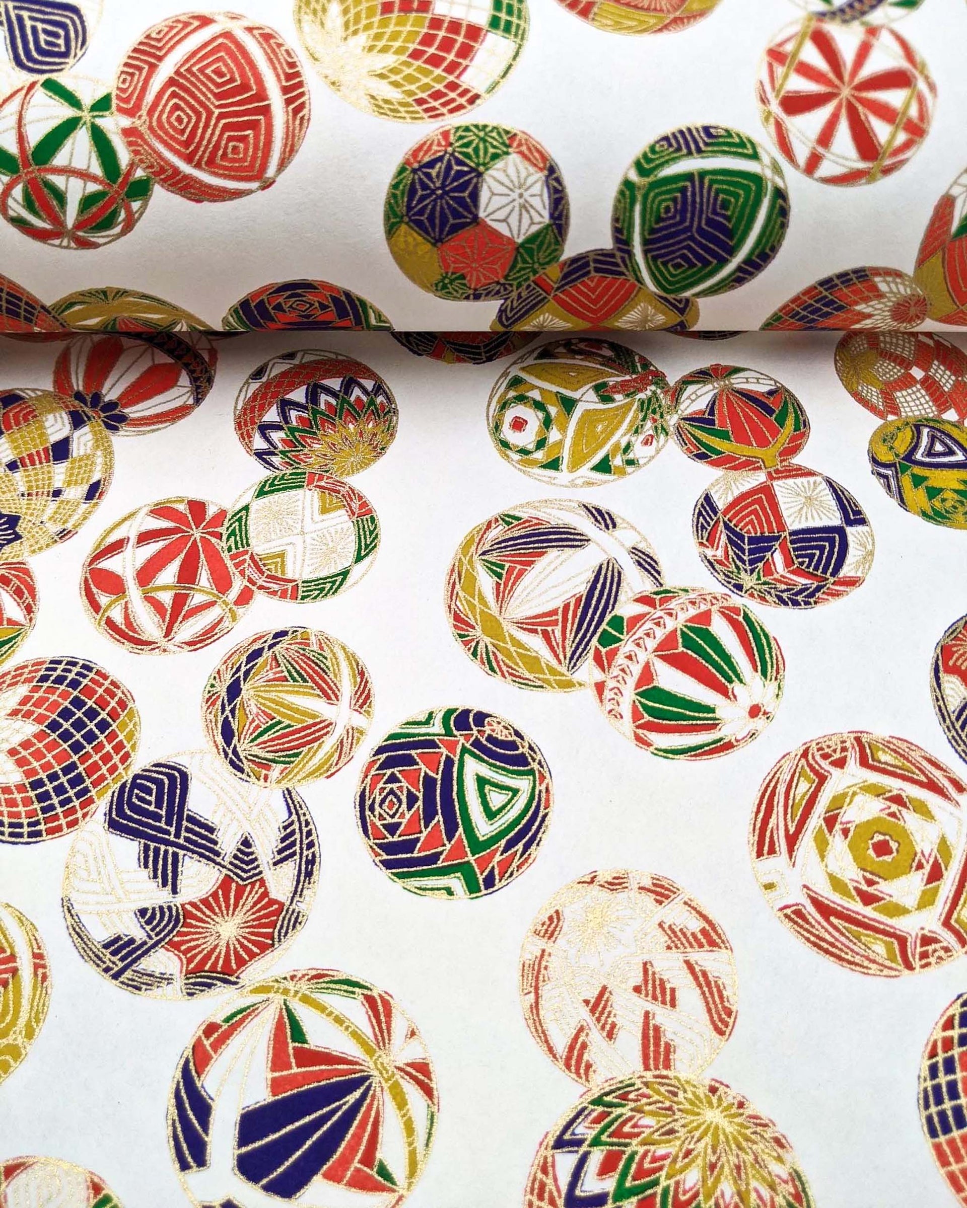 Japanese chiyogami paper featuring an assortment of colorful Japanese temari balls on a white background with metallic gold details.