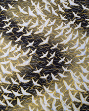 Japanese chiyogami paper featuring white flying cranes in a zigzag formation on a black and gold background with metallic gold and silver details.