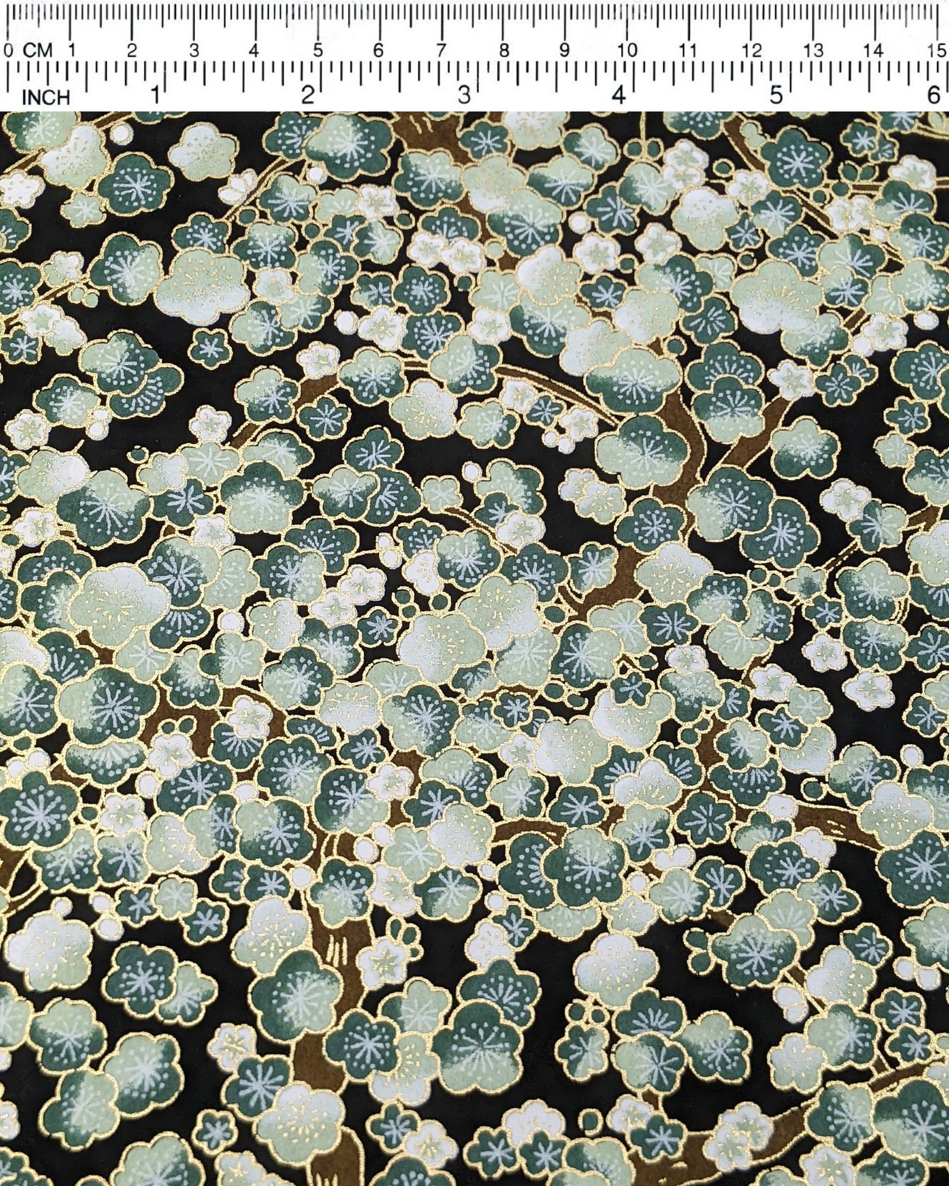 Japanese chiyogami paper featuring green plum blossom trees with brown branches on a black background with metallic gold details.