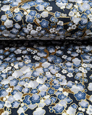 Japanese chiyogami paper featuring blue and gray plum blossom trees with brown branches on a dark blue background with metallic gold details.
