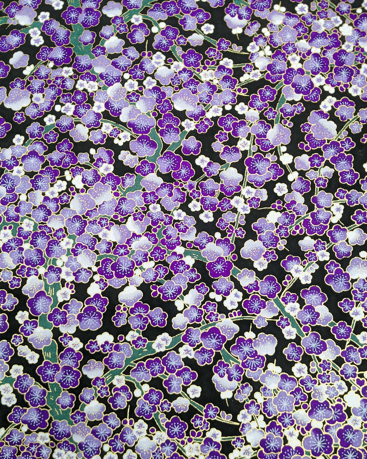 Japanese chiyogami paper featuring purple and white plum blossom trees with green branches on a black background with metallic gold details.