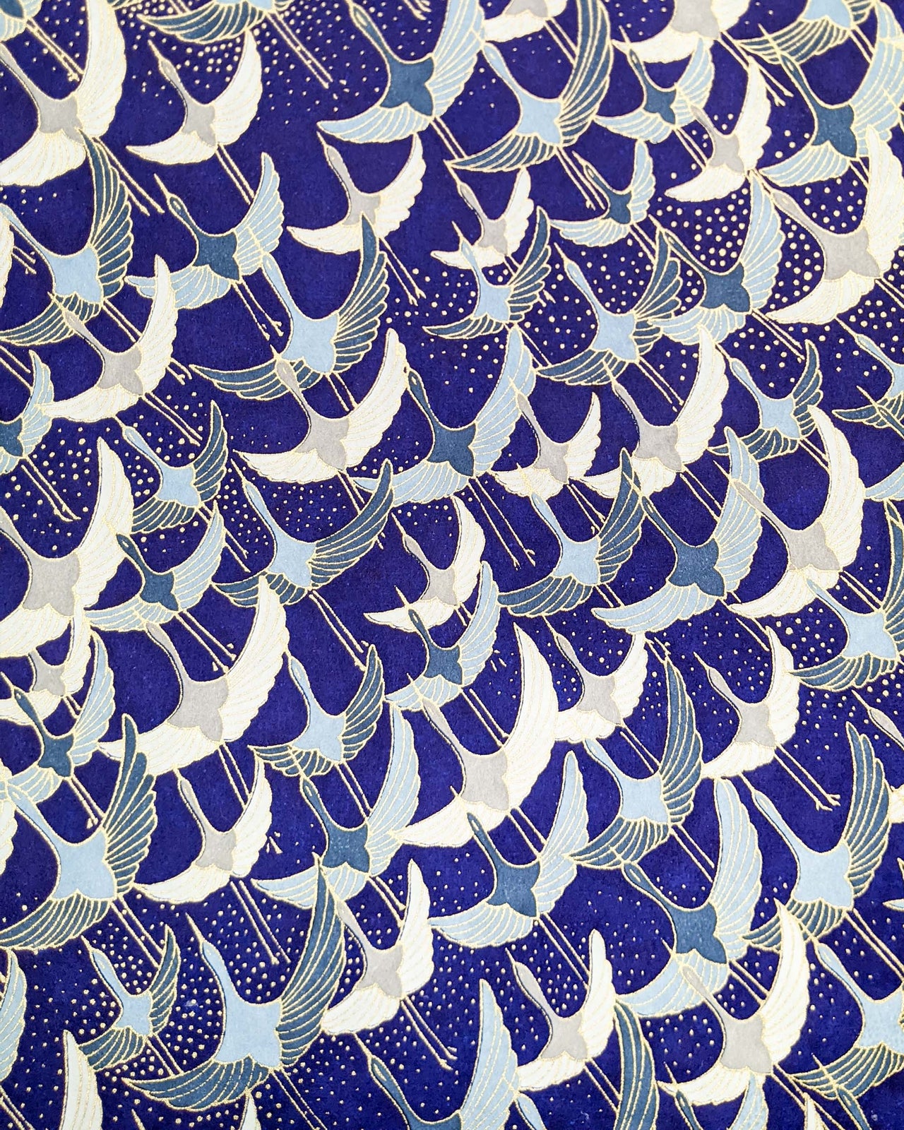 Japanese chiyogami paper featuring blue, gray, and white flying cranes on a blue background with metallic gold details. 