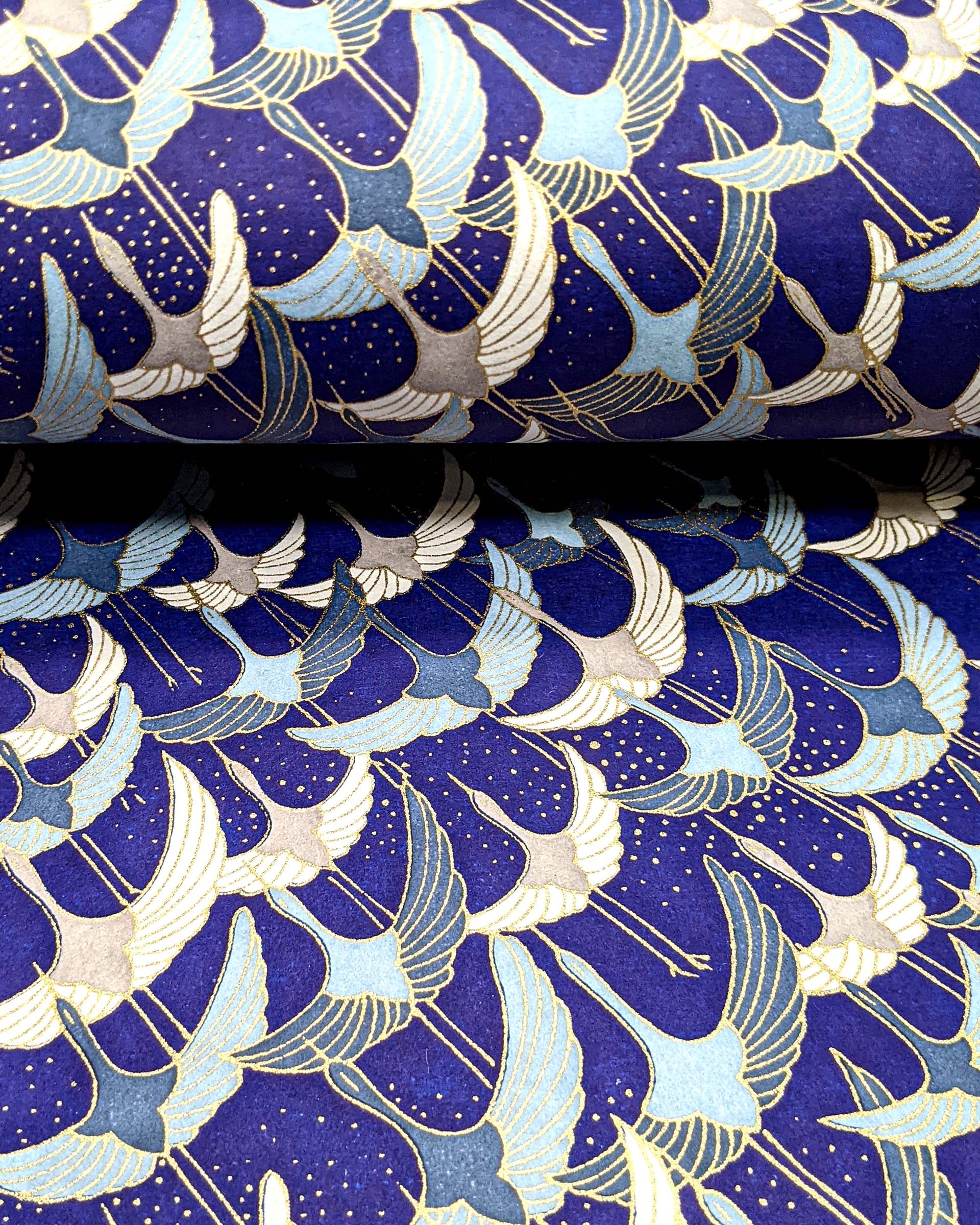 Japanese chiyogami paper featuring blue, gray, and white flying cranes on a blue background with metallic gold details. 