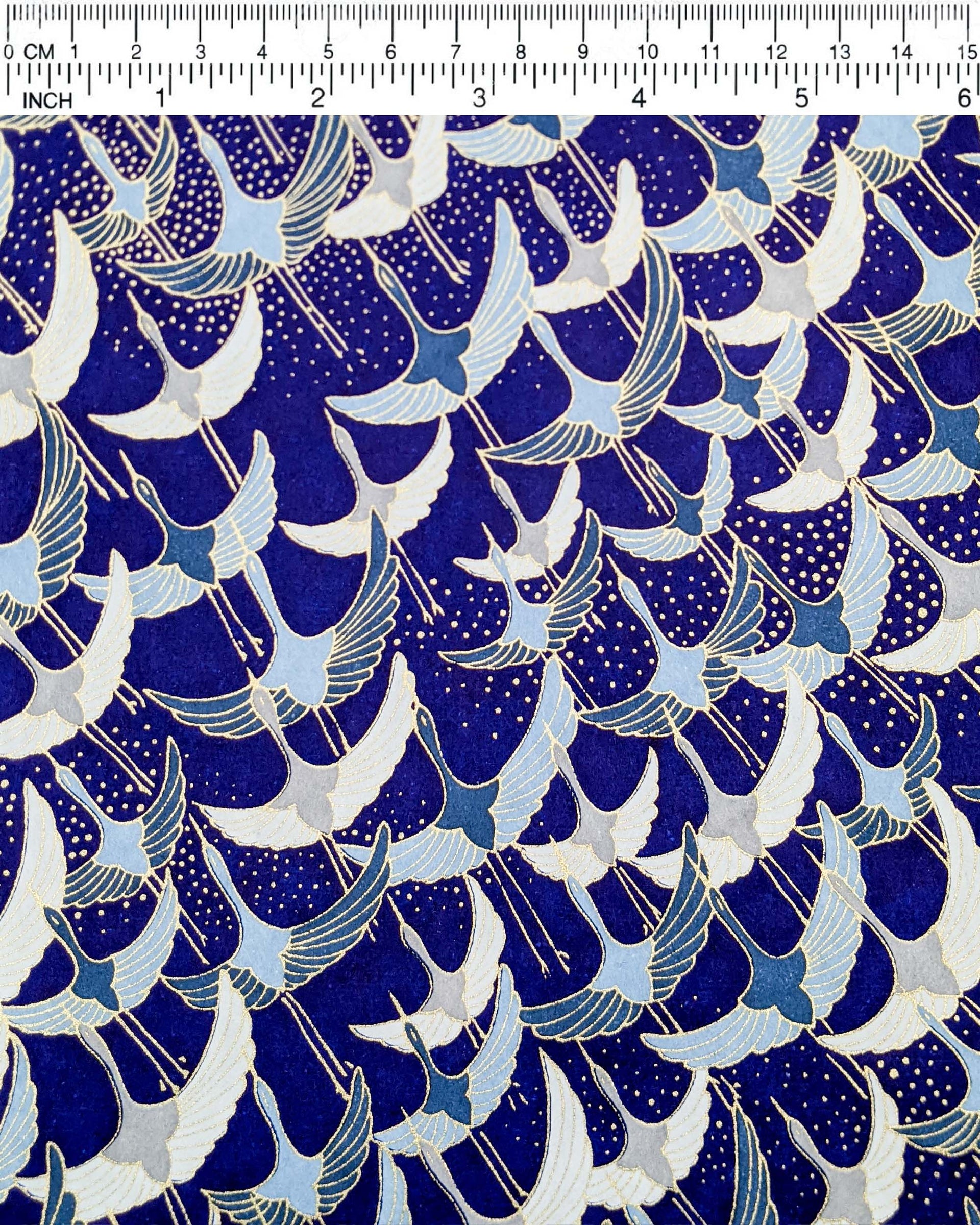 Japanese chiyogami paper featuring blue, gray, and white flying cranes on a blue background with metallic gold details. 